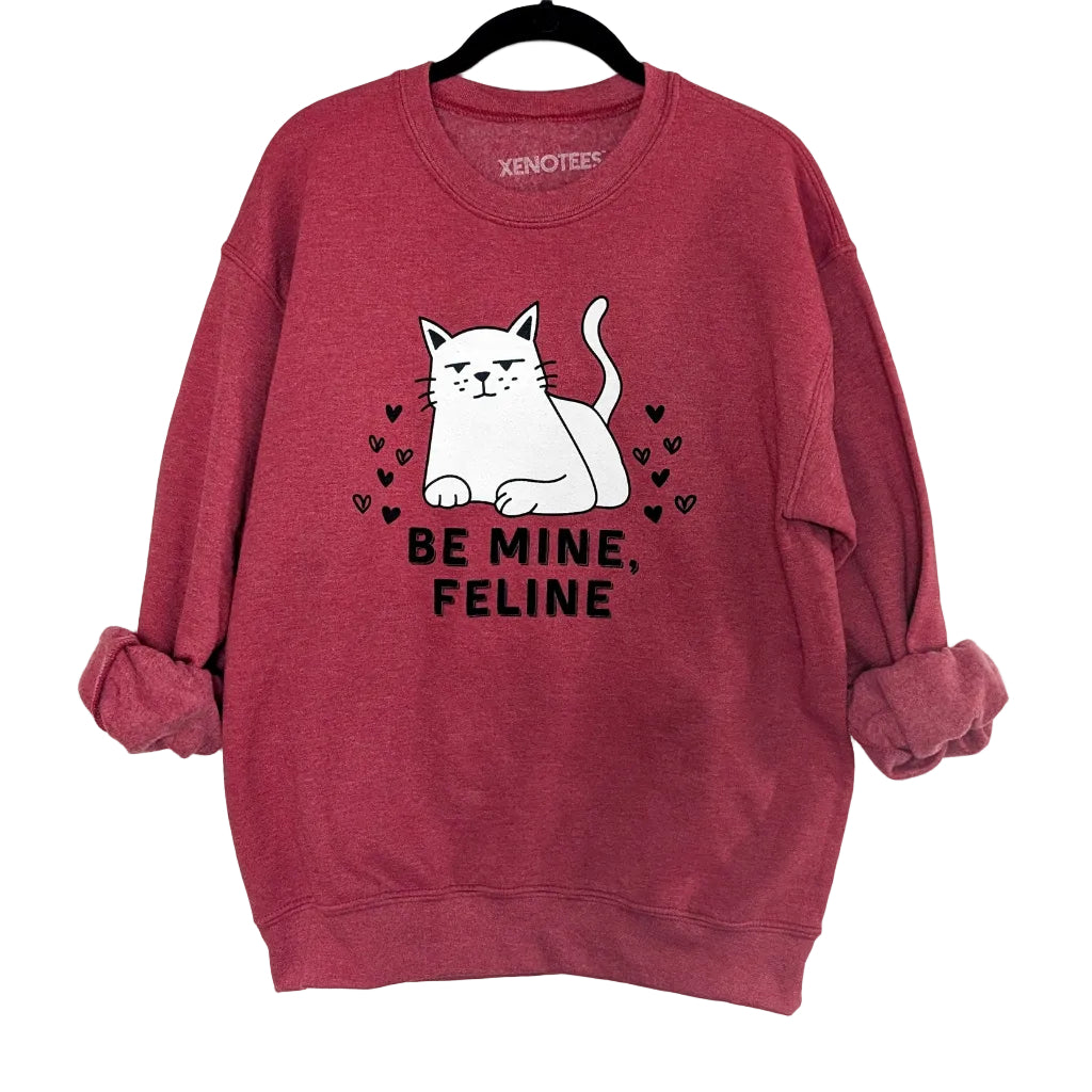 Red sweatshirt with a cat graphic and 'Be Mine, Feline' text on a white background